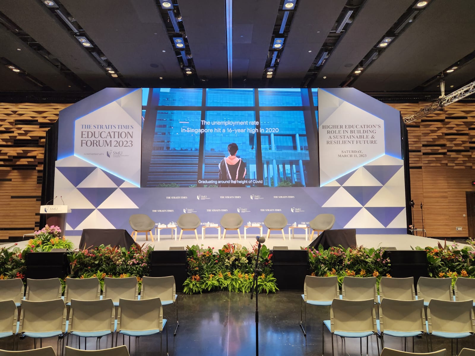 Corporate conference stage with professional AV setup, LED display and seated delegates