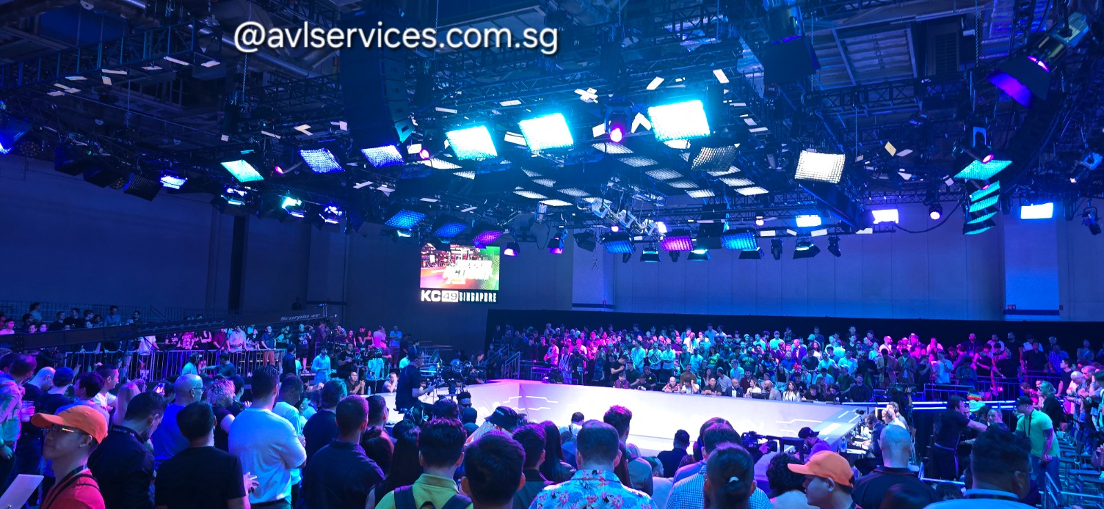 Karate Combat KC49 Singapore live broadcast — packed arena crowd lit by an overhead grid of blue and magenta broadcast panels